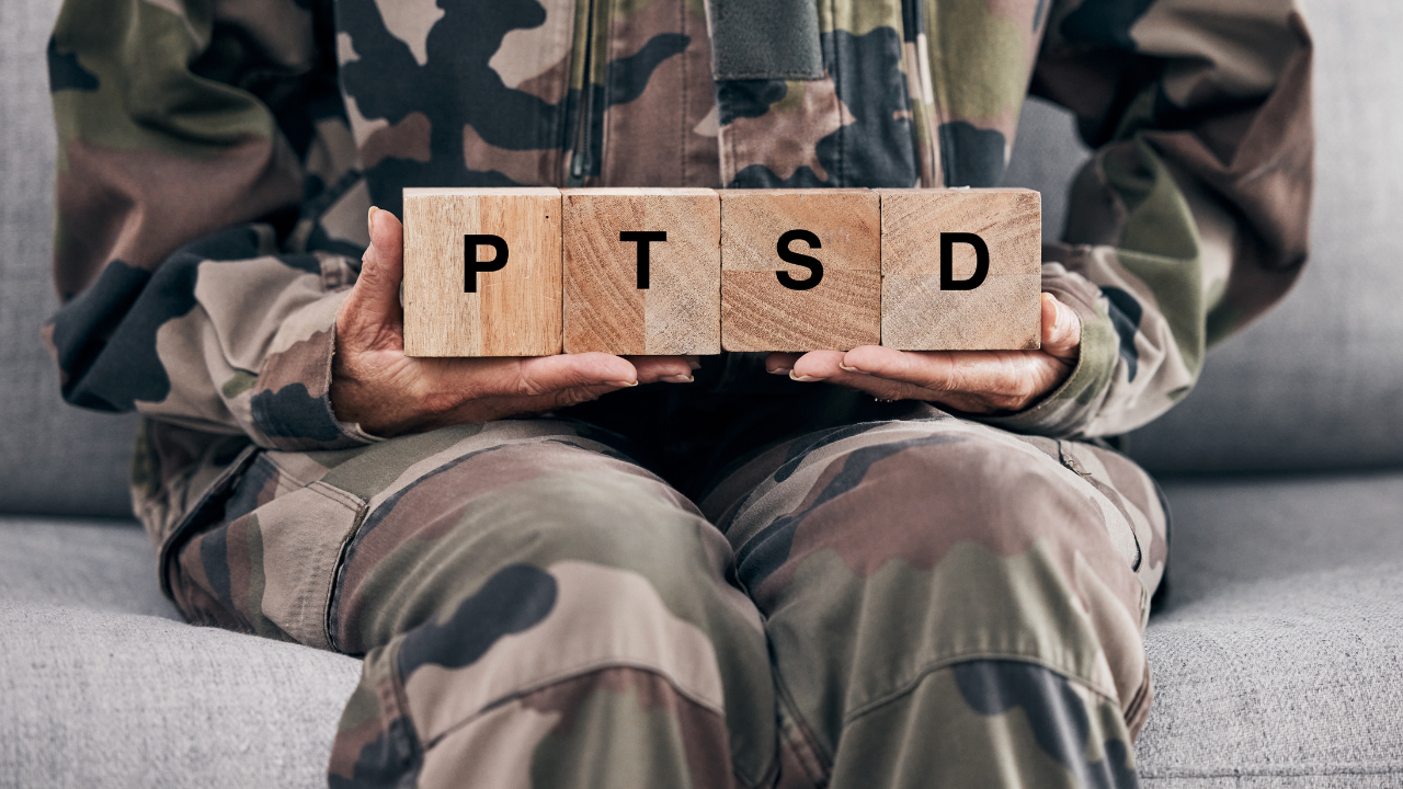 Soldier hands, holding wood block and sofa for therapy, ptsd and help for mental health problem from Ukraine war. Military professional, wooden sign or depression on couch after international combat. Image Credit: Adobe Stock Images/Lumeez/peopleimages.com