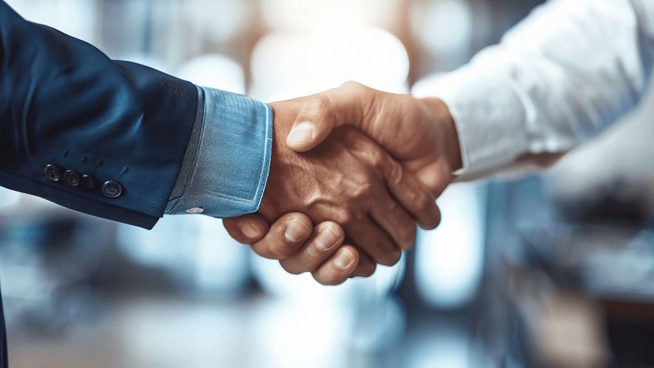 Sealing the Deal: A close-up handshake signifies trust and partnership in a modern business setting. Image Credit: Adobe Stock Images/WS Studio 1985